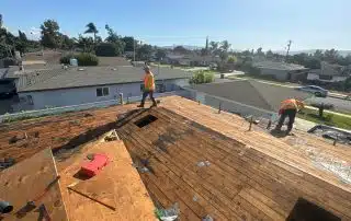 Affordable Shingle Replacement West Covina Workers repairing a residential rooftop under clear skies.