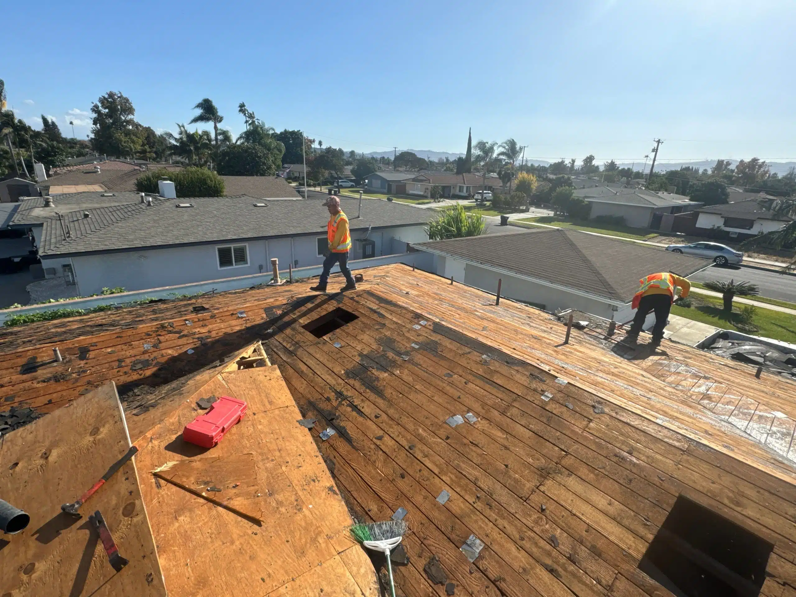 Workers repairing a residential rooftop under clear skies.