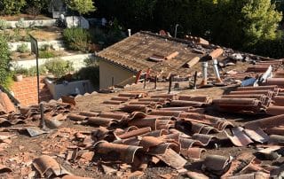 Damaged roof tiles near house with gardens.