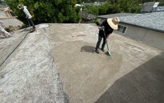 roofers applying new gravel to torched down roof