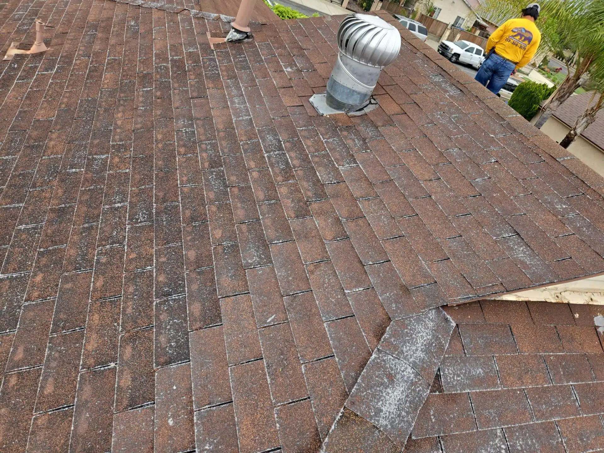 Damaged shingles Roof Repair & Construction Inc contractor replacing old shingles on a California home
