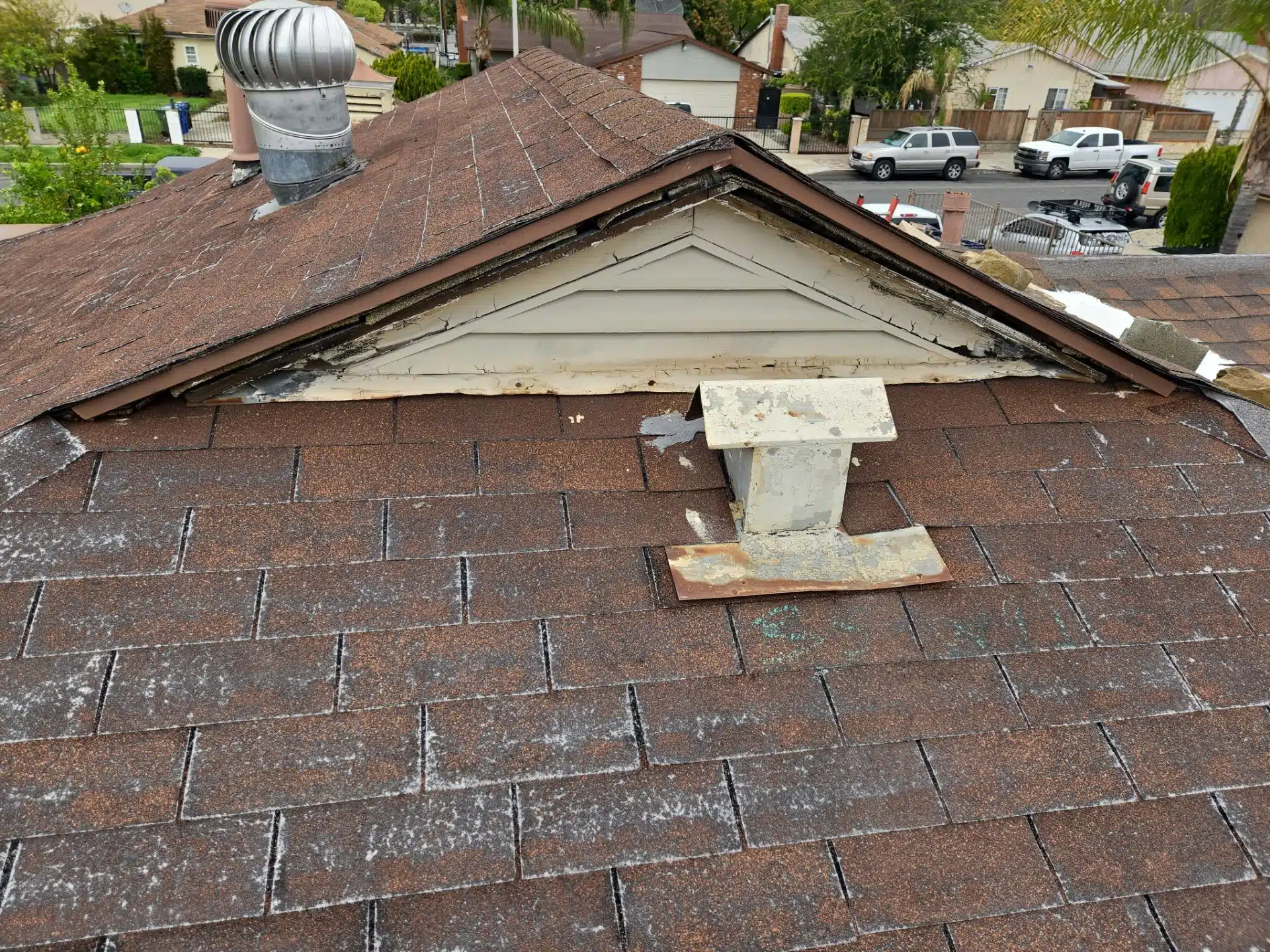 Damaged asphalt shingles on residential roof showing signs of wear
