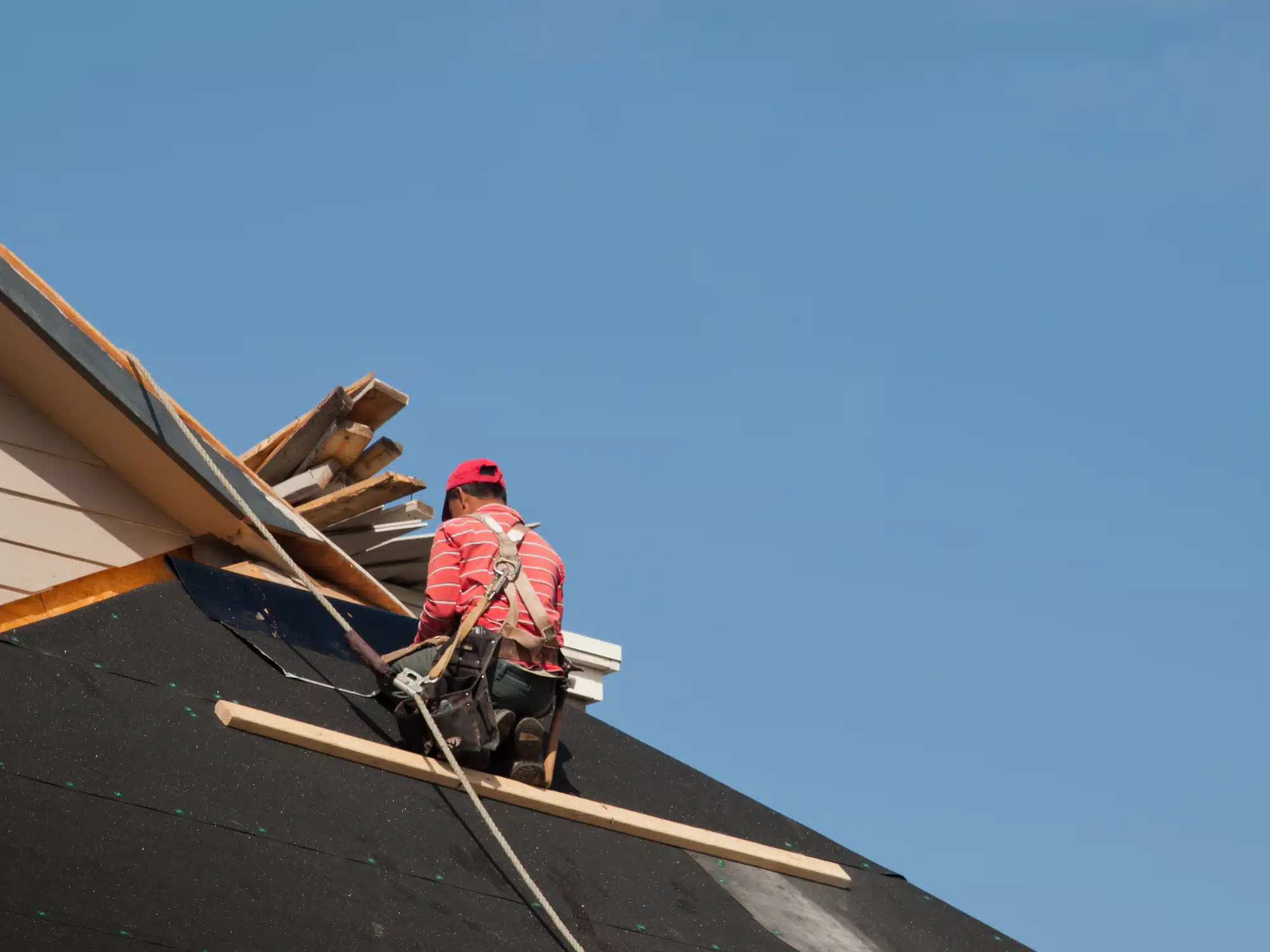 dreamstime_m_42042618 Construction worker installing roof shingles safely.
