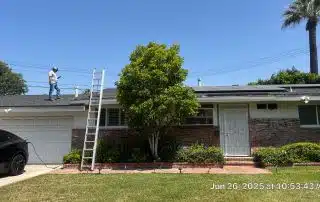 1-Jun 26 2025 10_53am-xfrQ Person inspecting roof with solar panels and ladder.