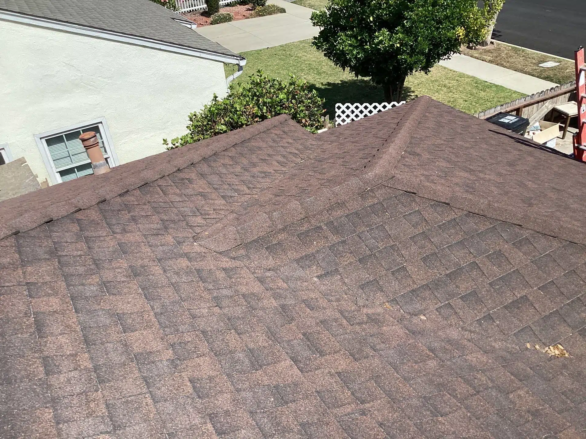 Brown shingle roof with residential background.