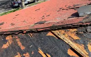 Damaged roof with purple blooming tree in neighborhood.