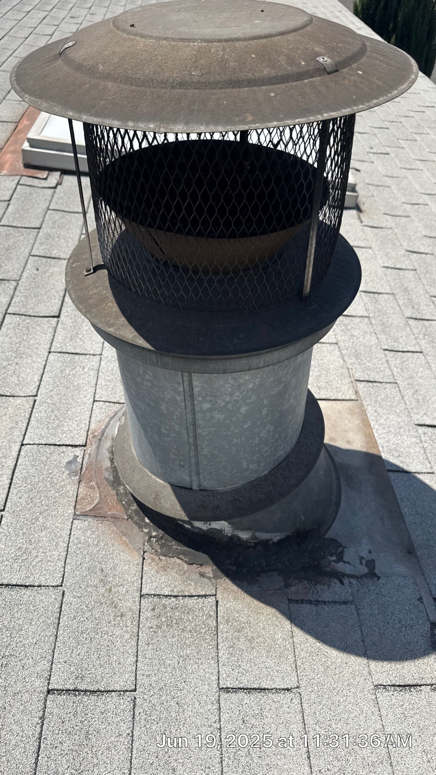 30-Jun 19 2025 11_31am-TtZW Metal chimney on shingled roof, sunny day