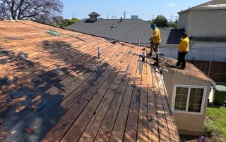Workers repairing roof on sunny day.