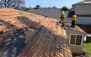 Workers repairing roof on sunny day.