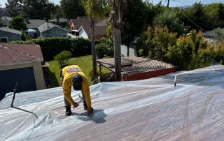 Worker securing roof under blue sky.
