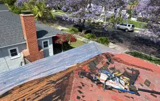 Rooftop repair with tools and purple trees visible.