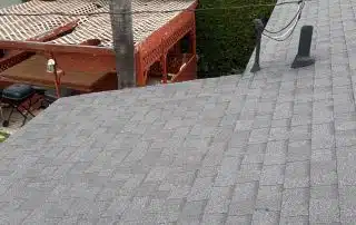 Gray rooftop with chimney and palm tree background.