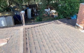 Brown shingle roof with chimney and backyard view.