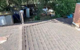 Brown shingle roof with chimney and backyard view.