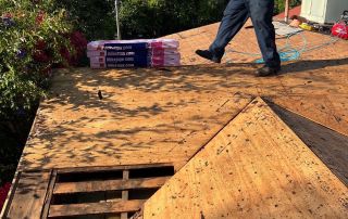 Worker inspecting roof with insulation materials.
