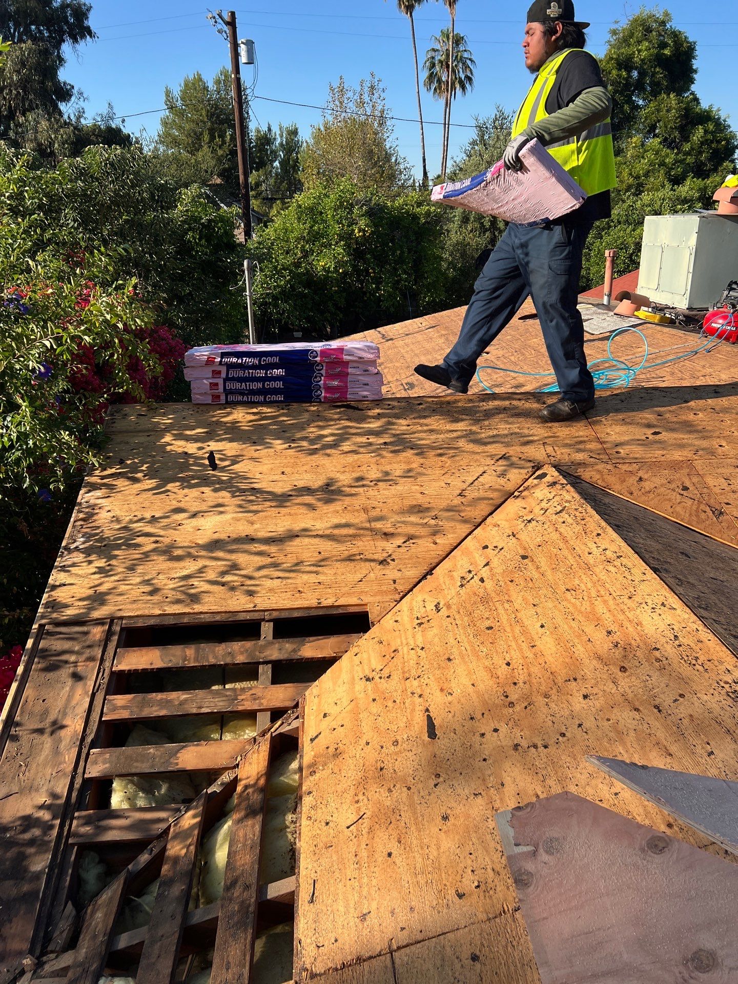 Worker inspecting roof with insulation materials.