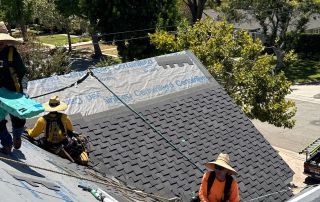 Roofers working on shingles, sunny day.