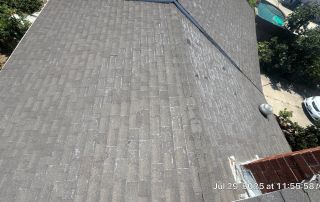 Aerial view of shingled roof with trees and pool.