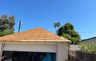Garage with sloped shingle roof, clear sky background.
