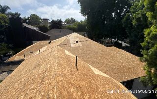 Plywood roof installation on sunny day, trees surrounding.