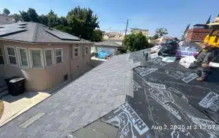 Rooftop construction, worker installing shingles.