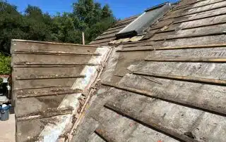 Partially repaired roof under clear blue sky.