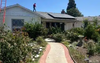 Person working on house roof with solar panels.