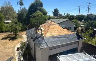 Workers installing roof shingles on a garage.