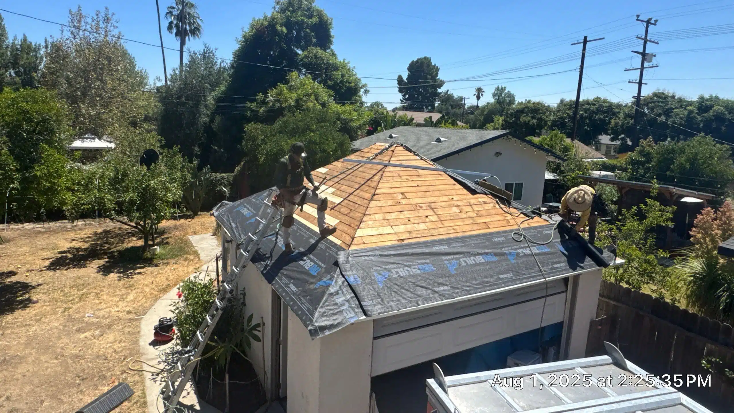 Workers installing roof shingles on a garage.