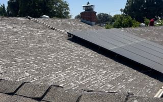 Roof with solar panel and chimney under blue sky