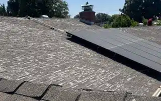 Roof with solar panel and chimney under blue sky