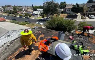 Roofers repairing residential roof on sunny day.