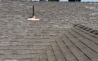 Asphalt shingled roof under clear sky view.