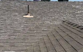 Asphalt shingled roof under clear sky view.