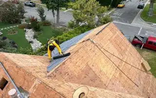 Worker repairing rooftop with wooden shingles.
