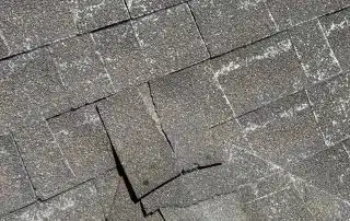 Close-up of damaged asphalt roof shingles.