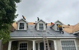 Workers installing new roof on house