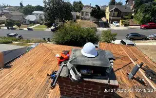 Rooftop construction tools and hard hat on chimney.