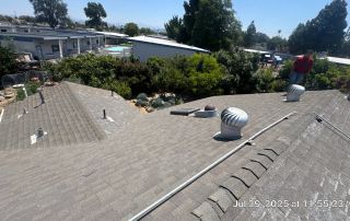 Rooftop view with vent and trees in background.