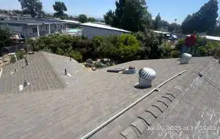 Rooftop view with vent and trees in background.