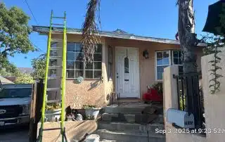 House with ladder and construction materials outside.