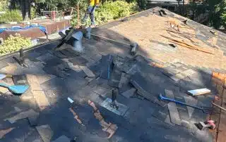 Worker repairing roof with mountain view background.