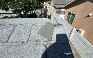 Damaged roof shingles with missing patch visible