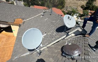 Rooftop with satellite dishes and damaged shingles.