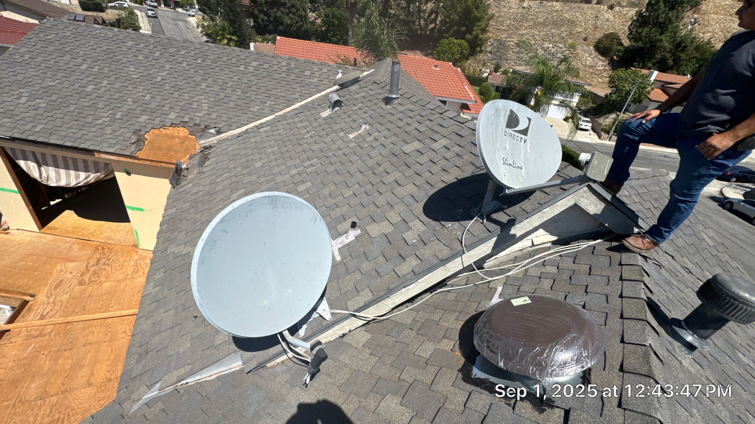 Rooftop with satellite dishes and damaged shingles.