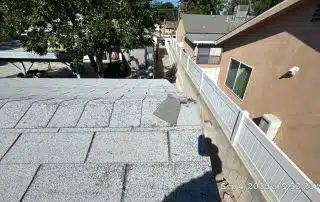 Damaged roof with loose shingles on sunny day.