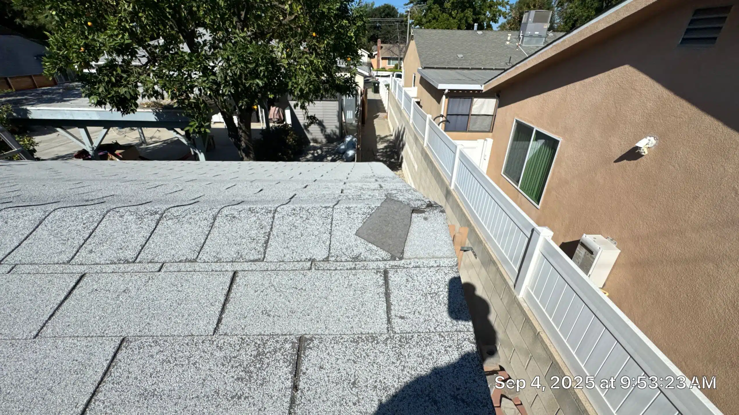 Damaged roof with loose shingles on sunny day.
