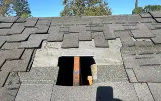 Roof with missing shingles and open hatch.