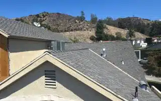 House rooftops with hills under clear blue sky