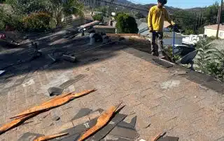 Roofer working on damaged roof under clear sky.
